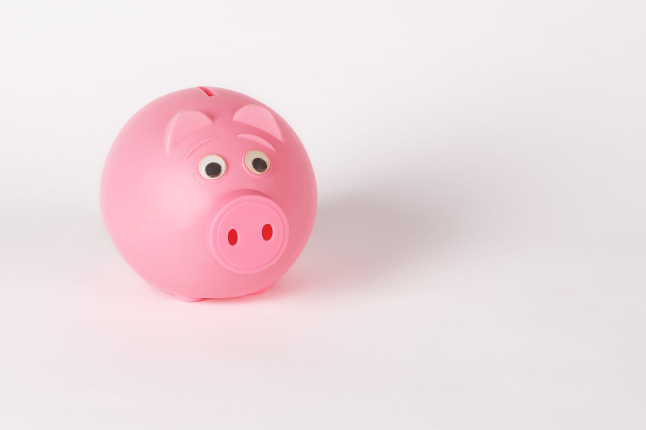 A cute pink piggy bank with googly eyes on a white background, symbolizing savings and finance.